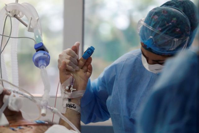 A member of the medical staff holds the hand of a patient at the intensive care unit (ICU) of the Sotiria hospital, amid the coronavirus disease (COVID-19) pandemic, in Athens, Greece, April 29, 2021. REUTERS/Giorgos Moutafis